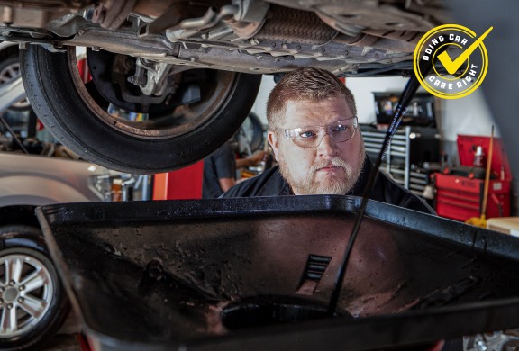 Meineke technician draining oil during an oil change service